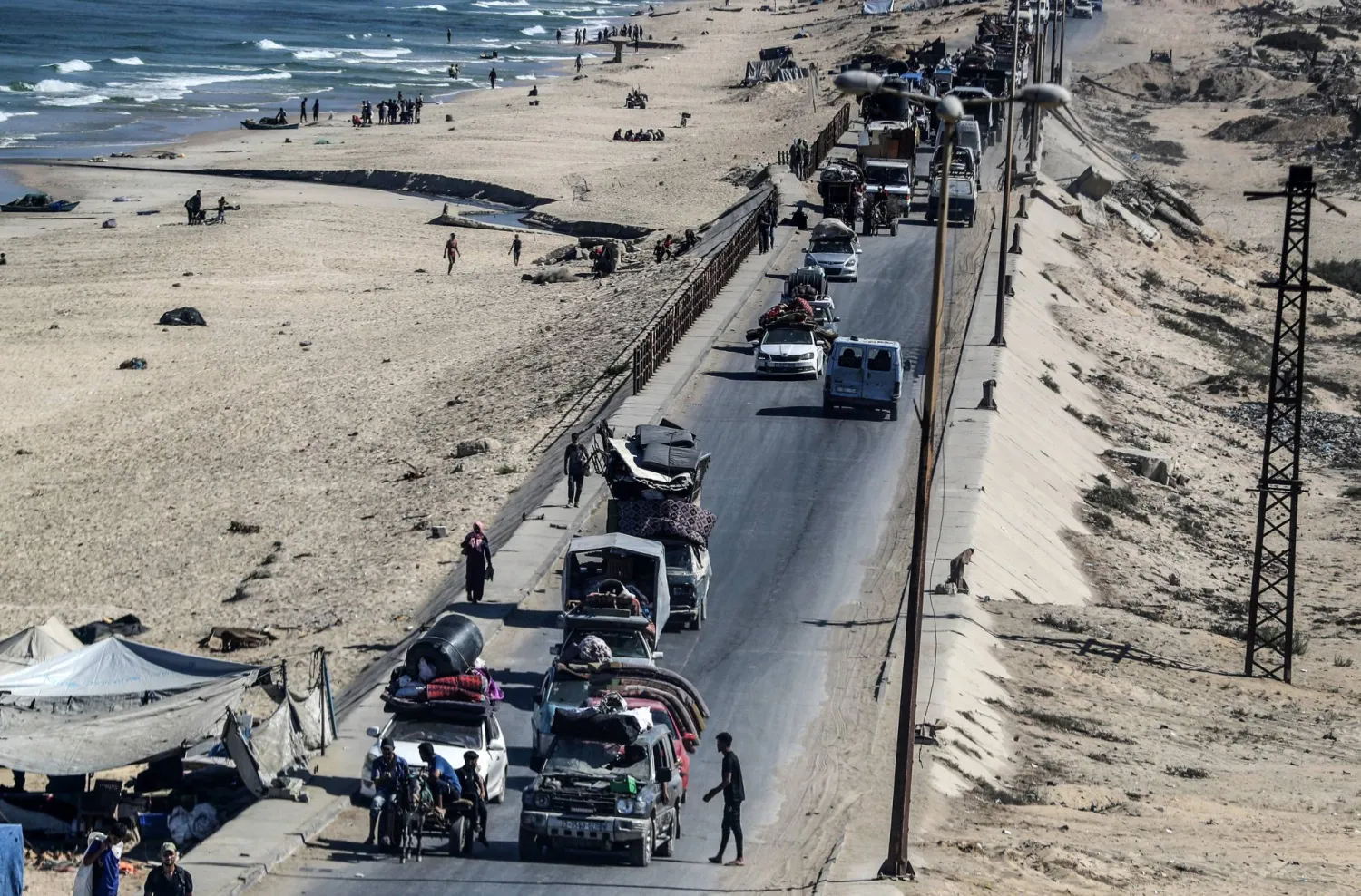 عربات تنقل فلسطينيين تتحرك في شارع الرشيد بمخيم النصيرات خلال النزوح من شمال غزة الجمعة (د.ب.أ)