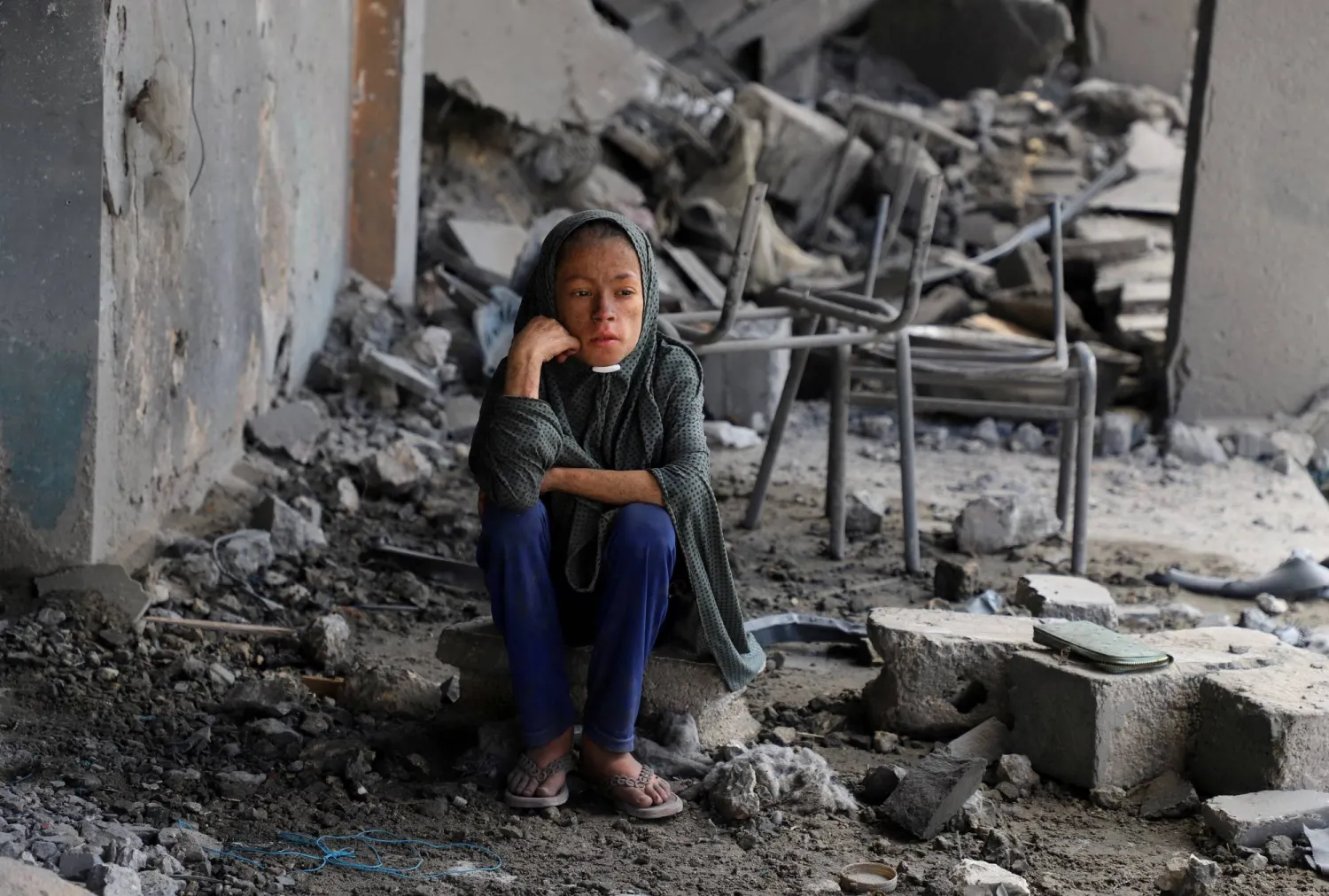 طفلة تجلس وسط الحطام في مدرسة تابعة للأمم المتحدة لجأ إليها النازحون بعد أن تعرضت لقصف إسرائيلي ليلي، وسط عملية عسكرية بحي الزيتون بمدينة غزة (رويترز)