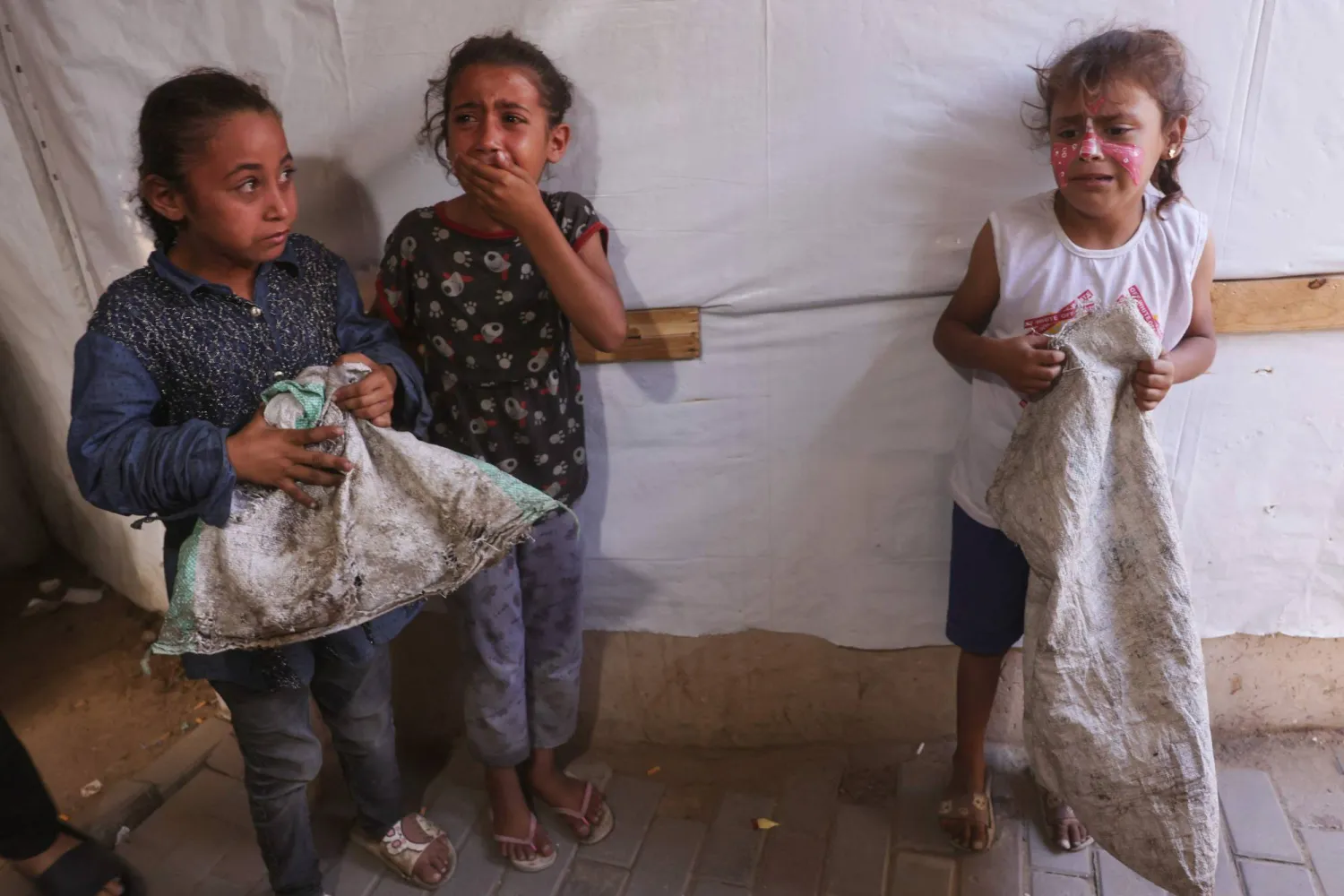 فتيات فلسطينيات يبكين بعد غارة إسرائيلية استهدفت خيمة يستخدمها نازحون داخل مستشفى في دير البلح وسط قطاع غزة أمس (أ.ف.ب)