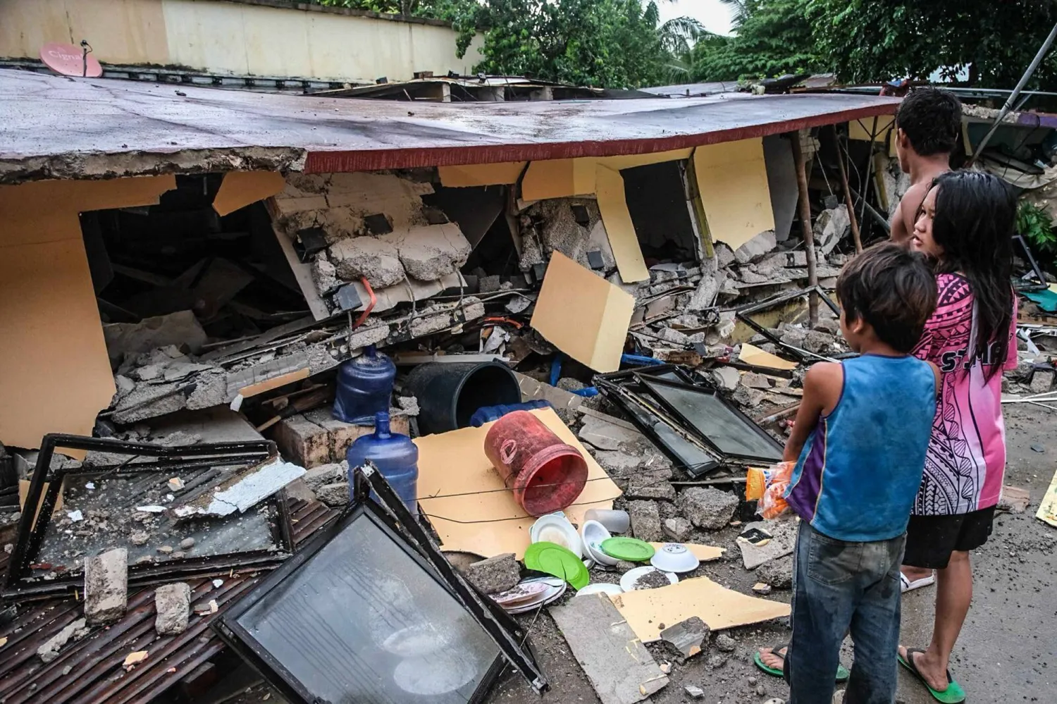 People look at a collapsed building in Bogo City, Cebu province, Philippines Wednesday, Oct.  1, 2025 after an offshore earthquake on late Tuesday. (AP Photo)