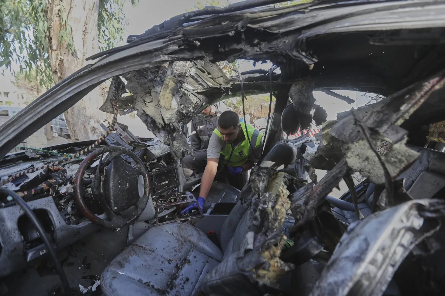 A civil defense worker inspects a damaged car hit the previous day in an Israeli drone strike that killed four members of the same family in Bint Jbeil, southern Lebanon, Monday, Sept. 22, 2025. (AP Photo/Mohammed Zaatari)