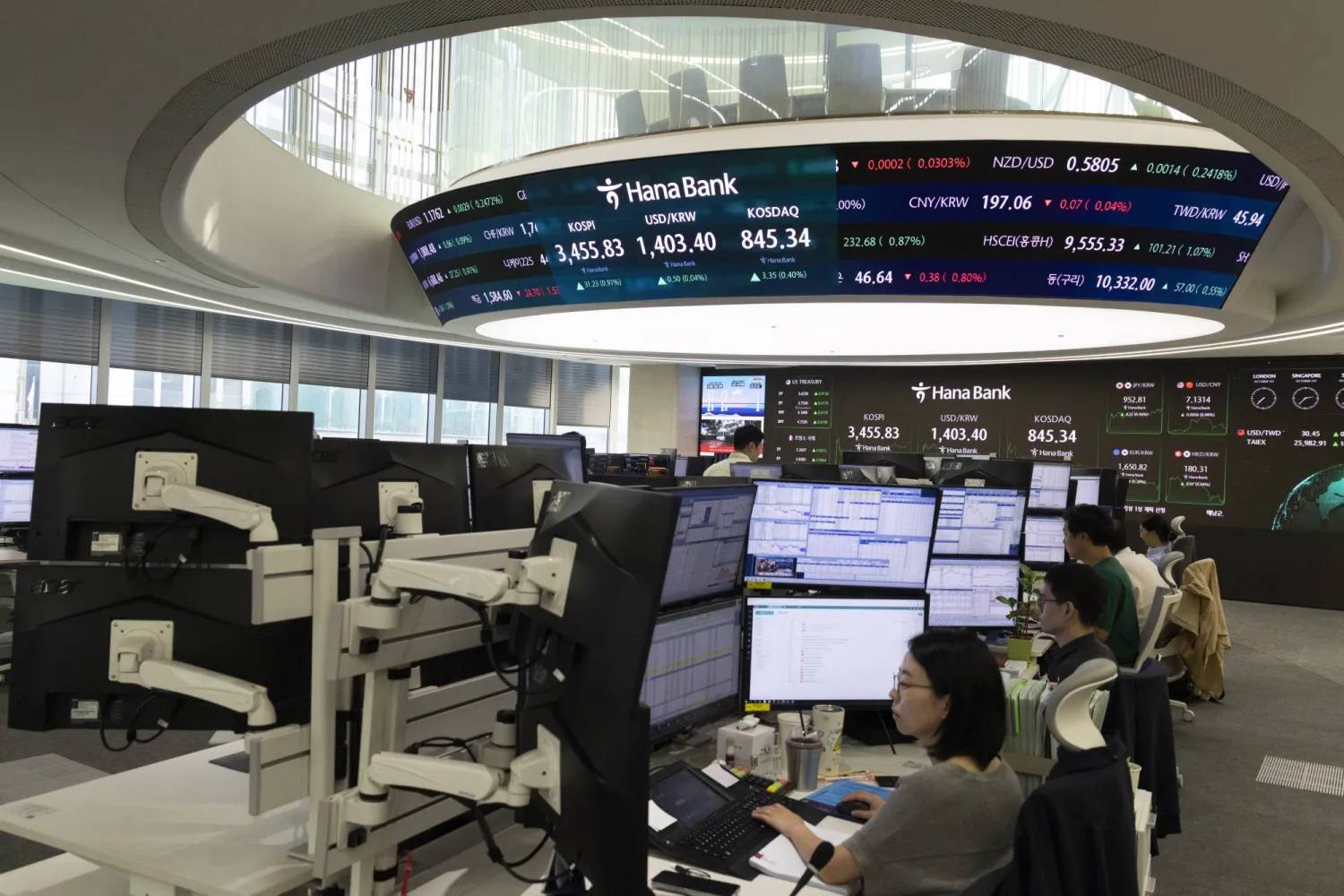 متداولون كوريون جنوبيون يعملون أمام شاشات في بنك «هانا» بالعاصمة سيول (إ.ب.أ)