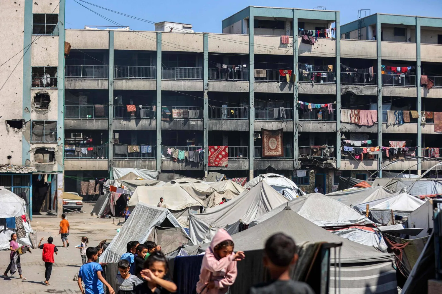 TOPSHOT - Tents sheltering people displaced by conflict are pitched in the yard of a school run by the United Nations Relief and Works Agency for Palestine Refugees (UNRWA) in Khan Yunis in the southern Gaza Strip on September 30, 2025. (Photo by Omar AL-QATTAA / AFP)