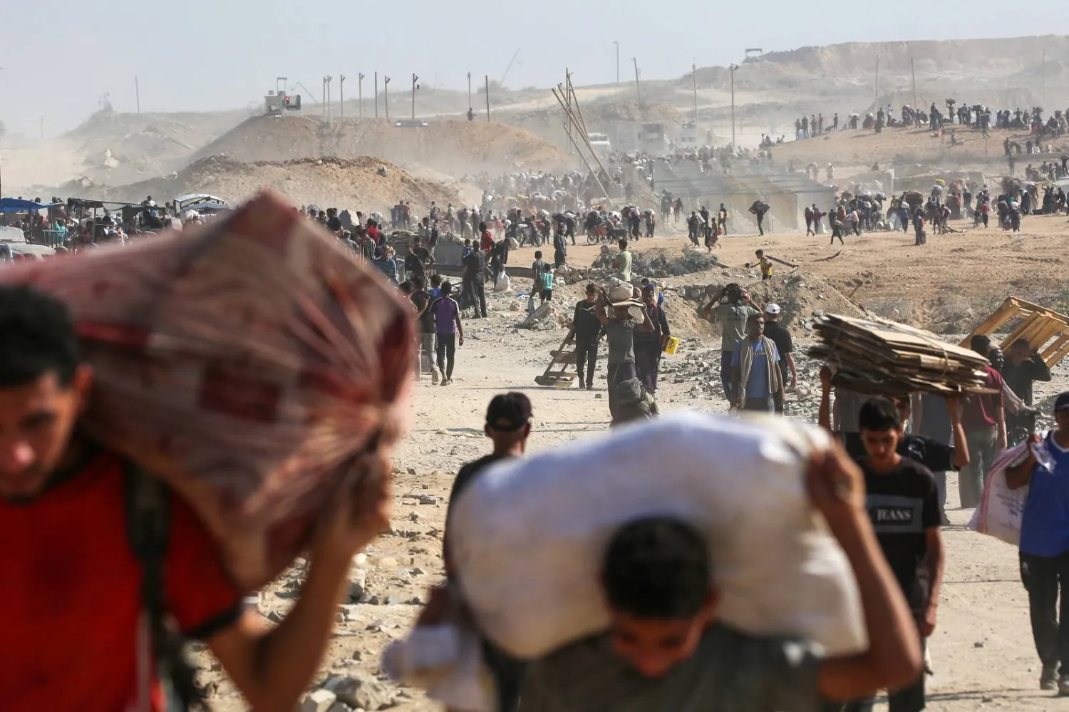 فلسطينيون يسيرون حاملين أكياساً من المساعدات الإنسانية في النصيرات (أ.ف.ب)