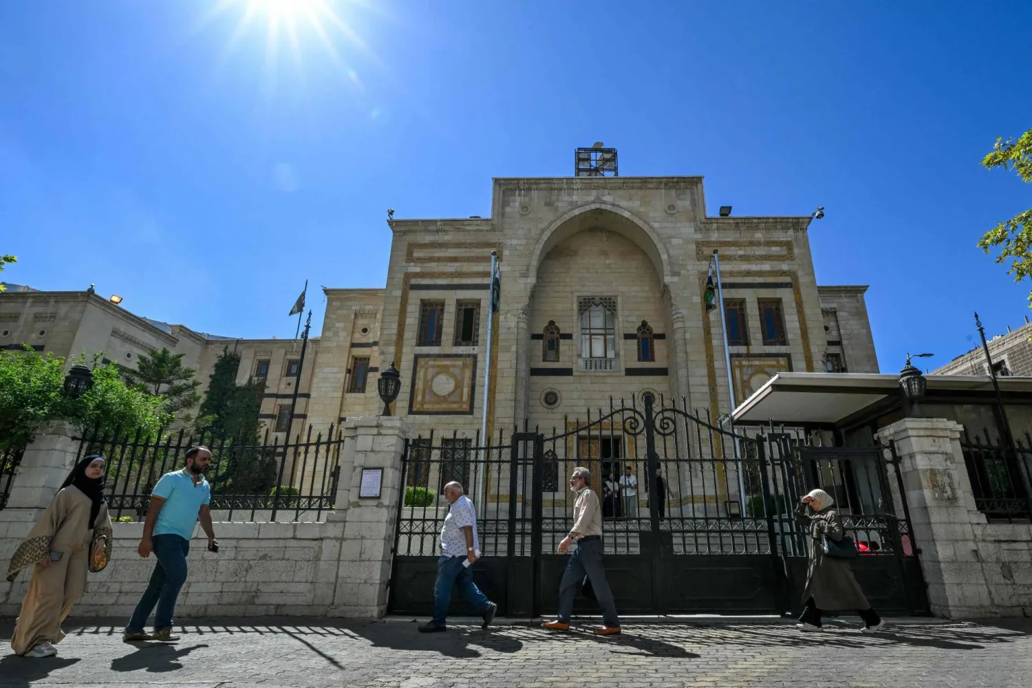 أشخاص يعبرون مبنى مجلس الشعب في دمشق الأربعاء (أ.ف.ب)