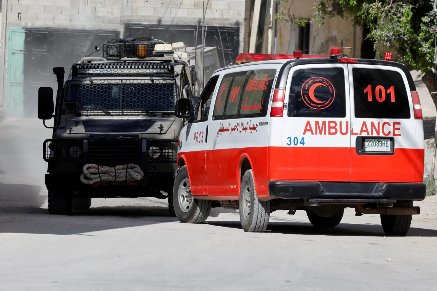 آلية عسكرية إسرائيلية تقف قرب سيارة إسعاف تتبع الهلال الأحمر الفلسطيني خلال اقتحام الجيش الإسرائيلي لمخيم الفارعة قرب طوباس بالضفة الغربية (رويترز) 