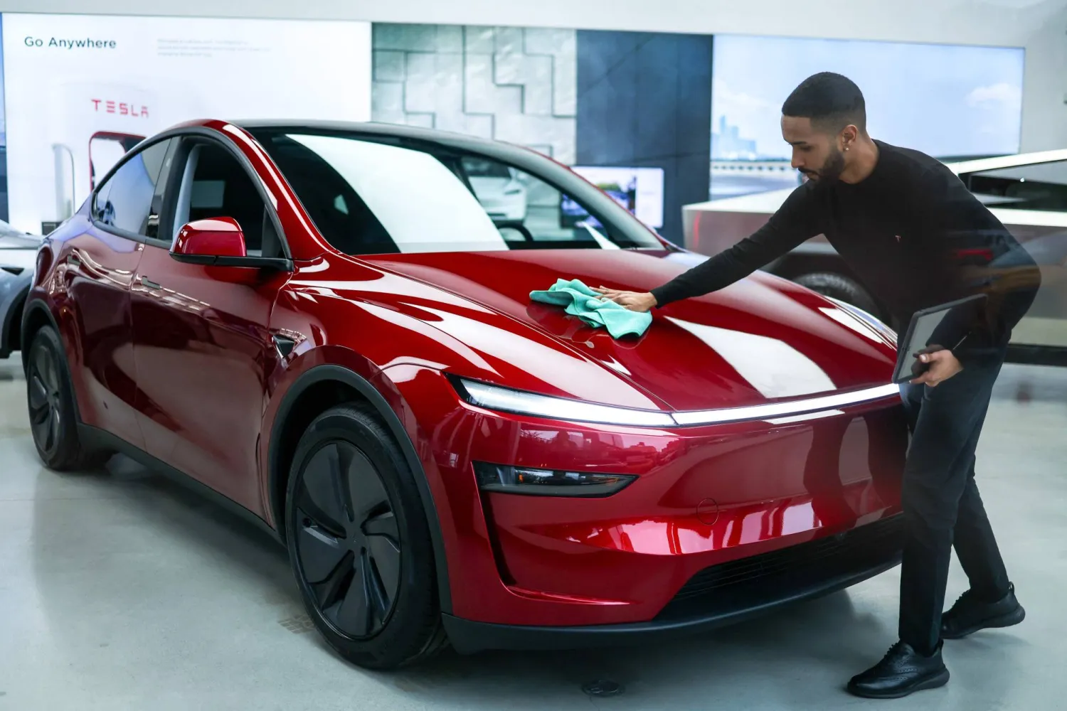 موظف ينظف سيارة «تسلا» في صالة عرض بمدينة نيويورك الأميركية (أ.ف.ب)