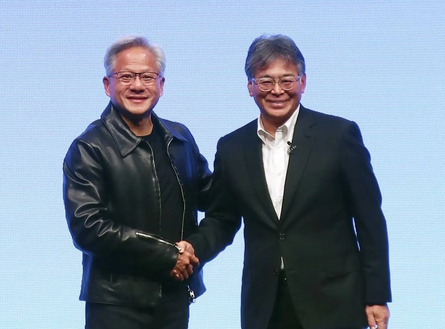 Nvidia Chief Executive Jensen Huang, left, and Fujitsu Chief Executive Takahito Tokita shake hands during an announcement in Tokyo Friday, Oct. 3, 2025. (Kyodo News via AP)