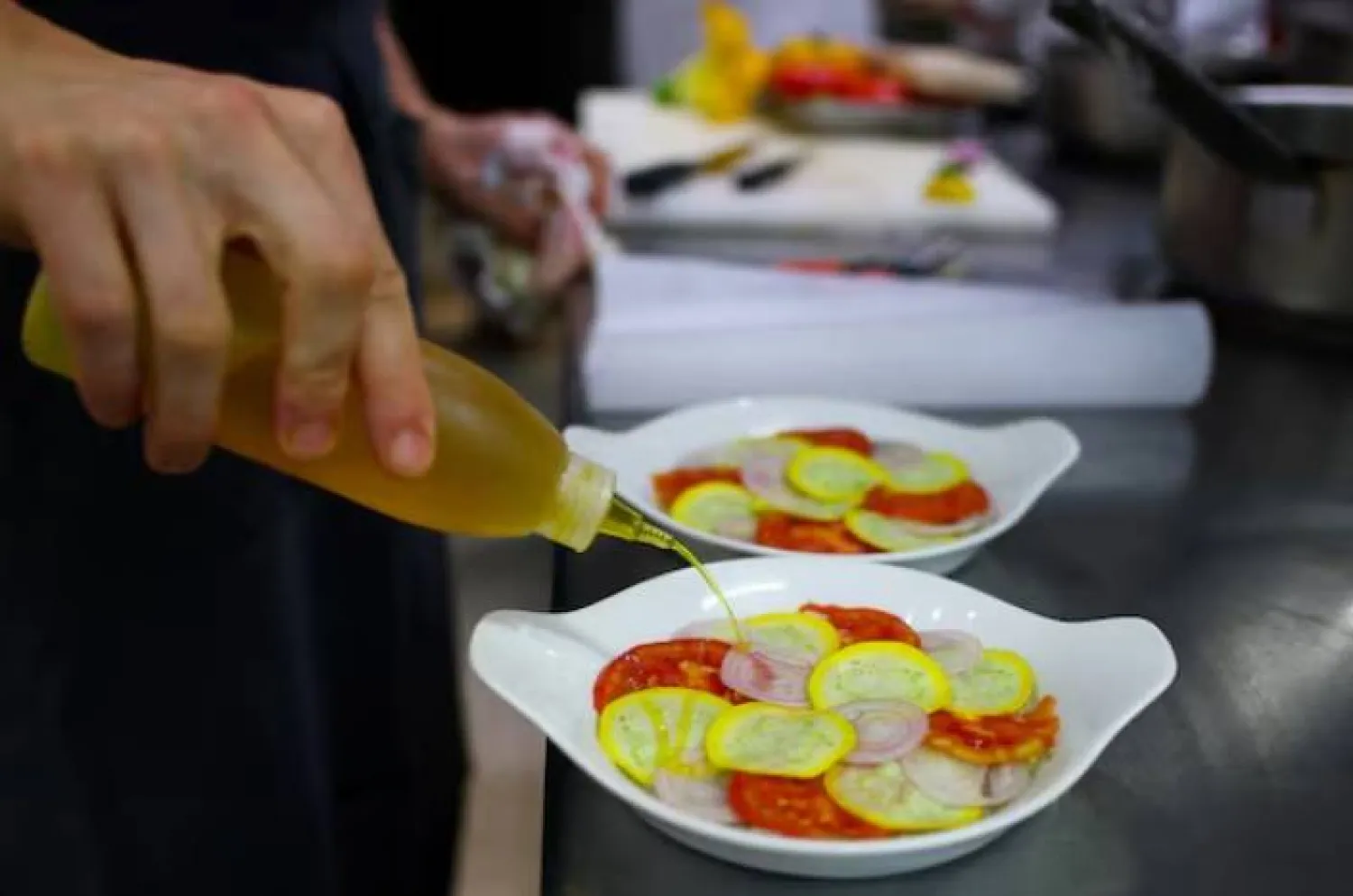 طاهٍ يحضّر الأطباق في مطبخ أحد المطاعم بباريس (رويترز)