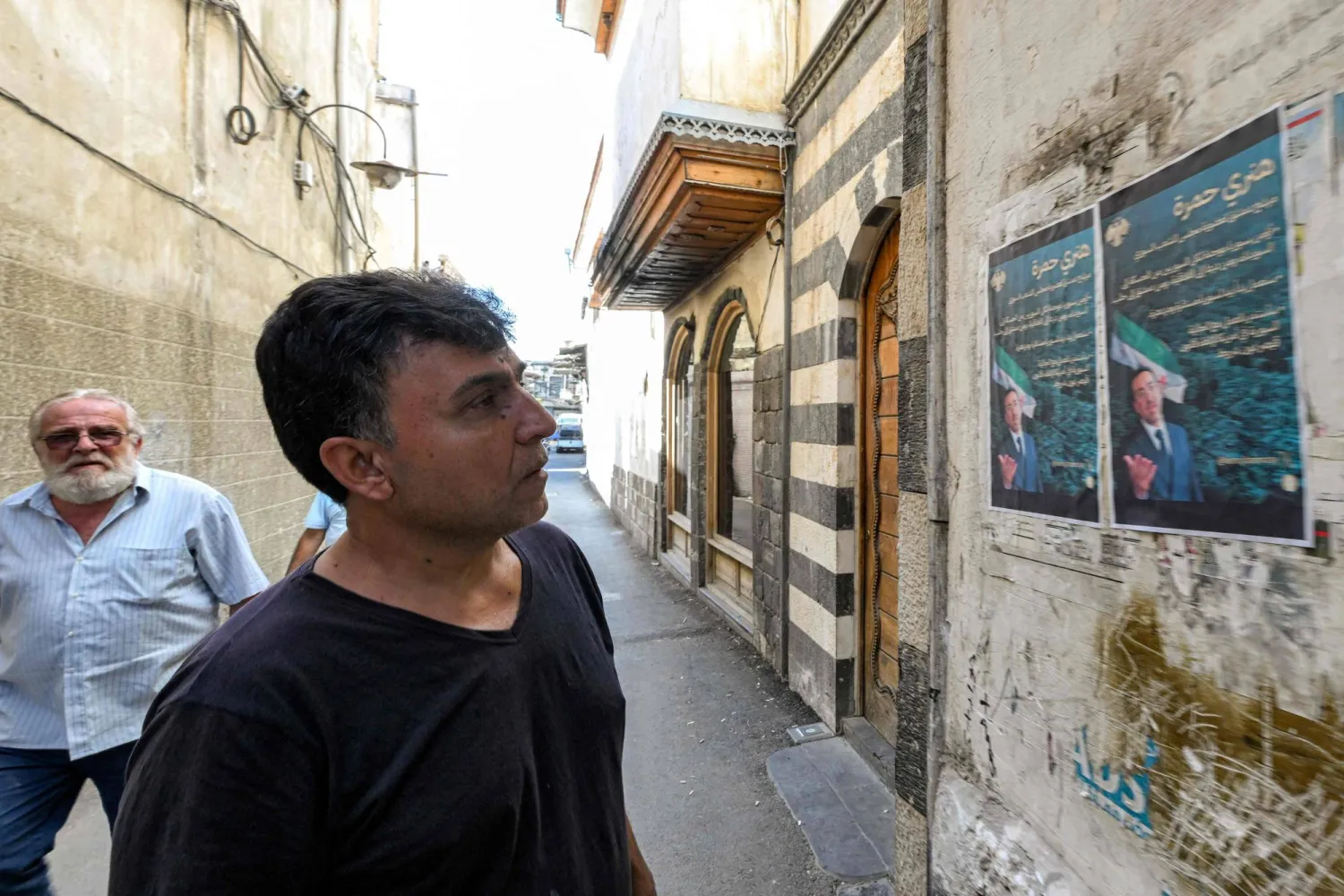 سوري ينظر لملصق دعائي للسوري الأميركي هنري حمرة أول يهودي يرشح نفسه لعضوية مجلس الشعب منذ عقود (أ.ف.ب)