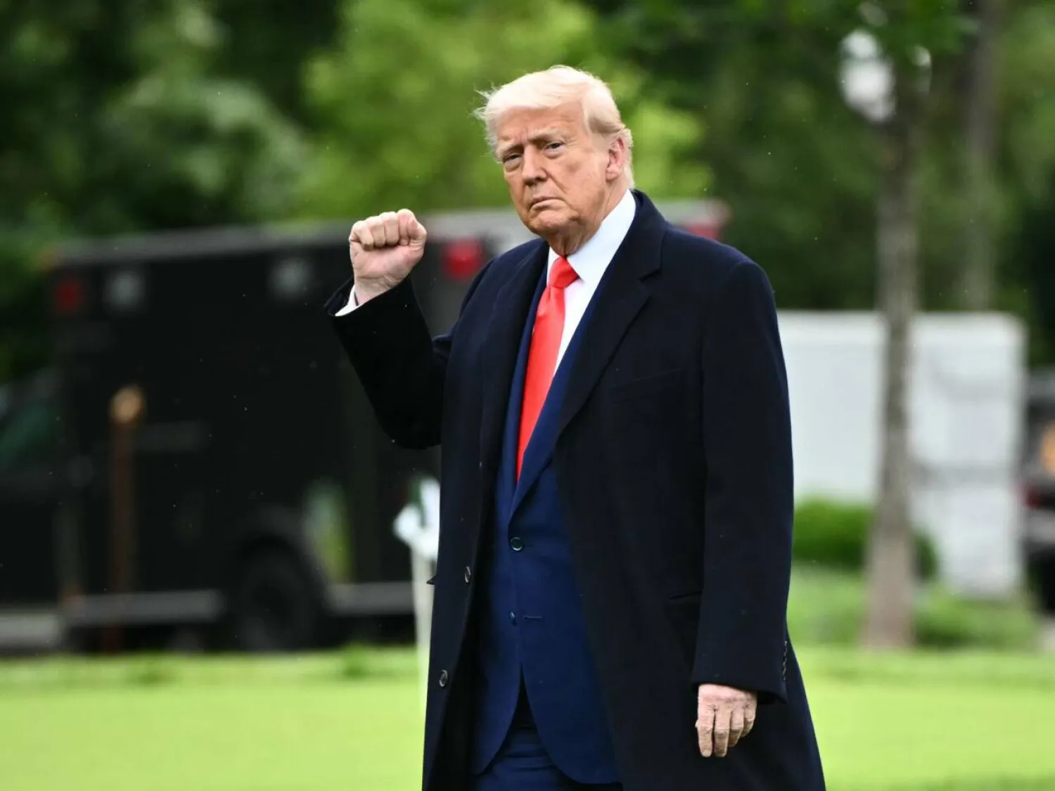 ترمب يرفع قبضته أثناء توجهه نحو طائرة الهليكوبتر الرسمية مارين وان على حديقة البيت الأبيض (أ.ف.ب)