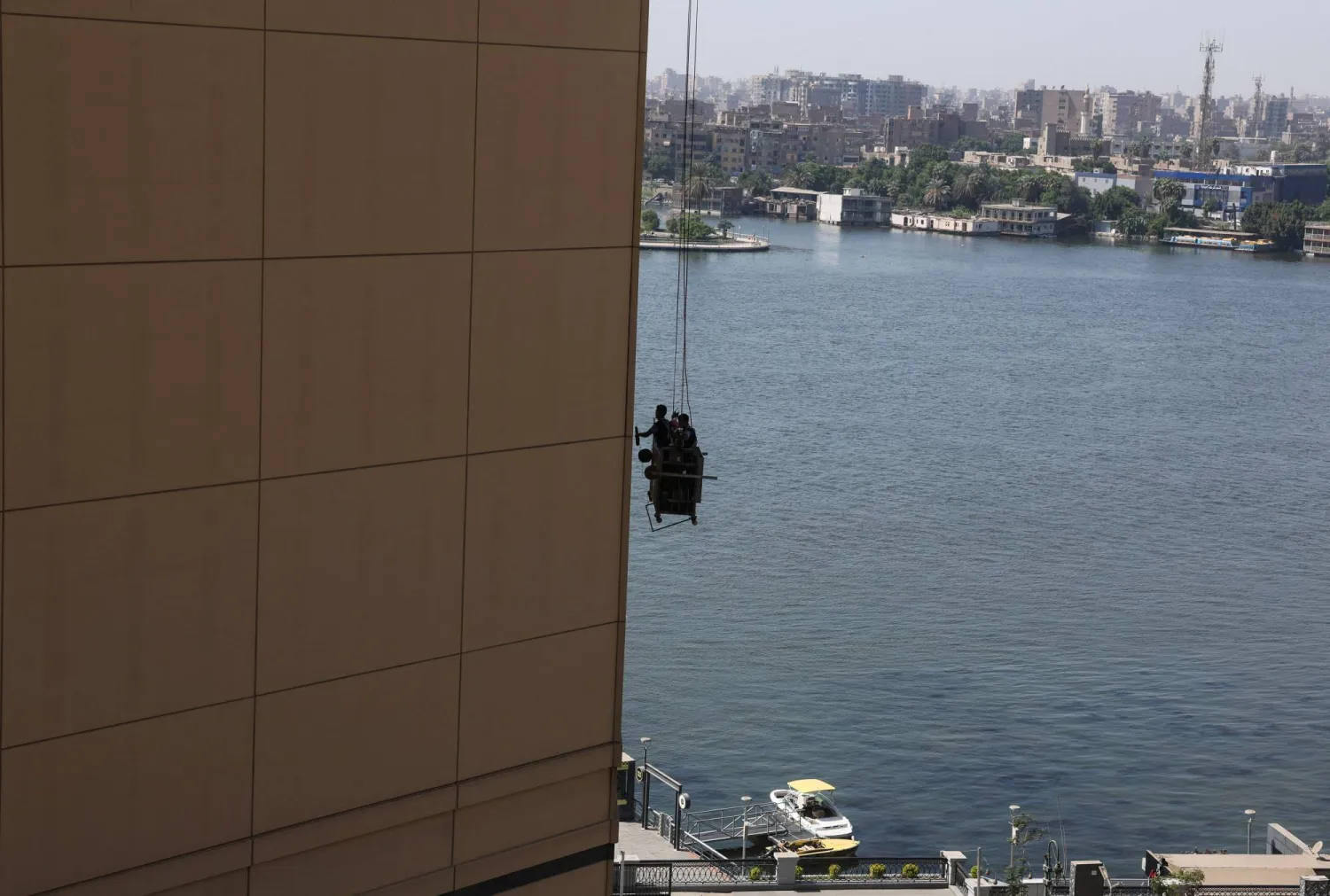 عمال مصريون ينظفون مبنى برج نايل سيتي بالقرب من نهر النيل (رويترز)