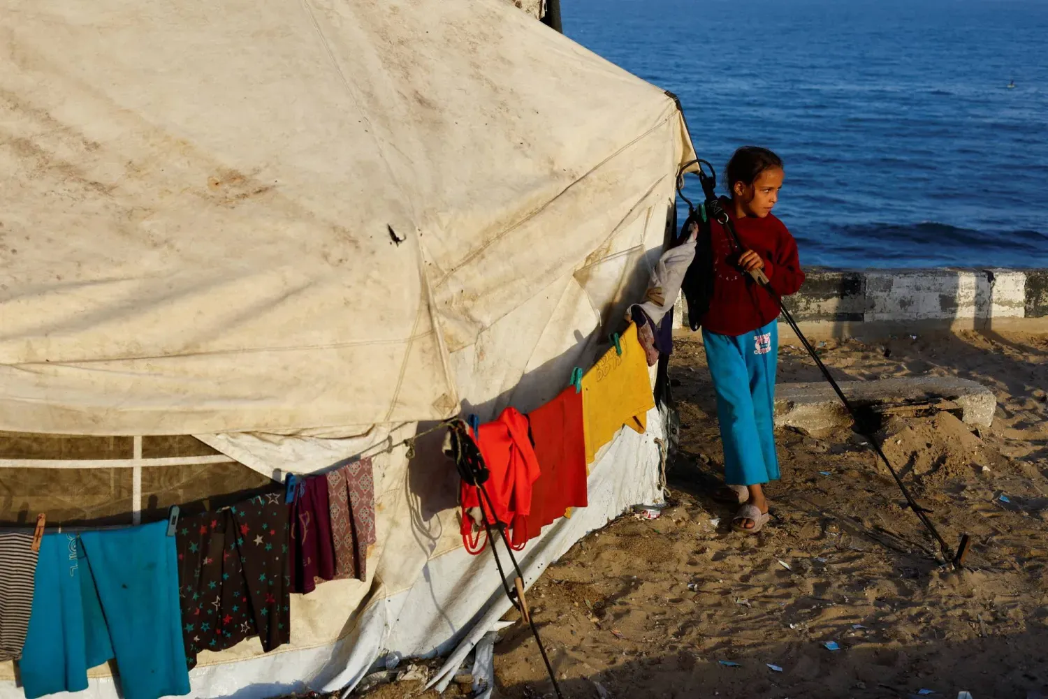 Gazze sahilinde kaldığı çadırın yanında duran yerinden edilmiş Filistinli bir kız çocuğu (Reuters)