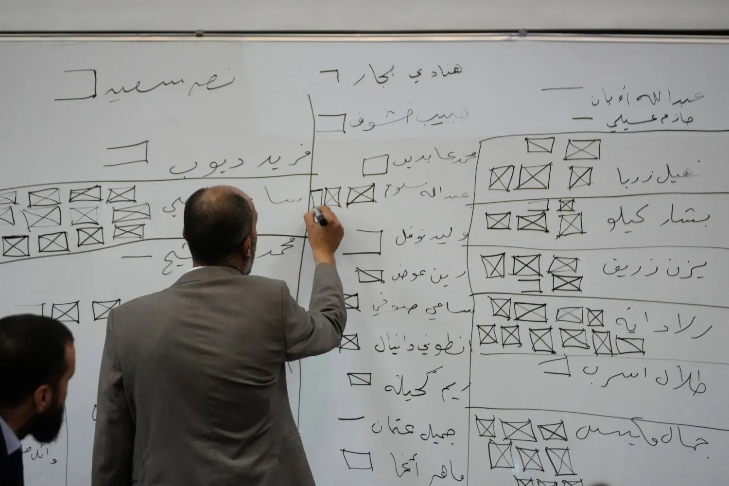 مسؤول انتخابي سوري يوثق على السبورة أثناء فرز الأصوات بعد وقت قصير من إغلاق مراكز الاقتراع في محافظة اللاذقية الأحد (أ.ب)