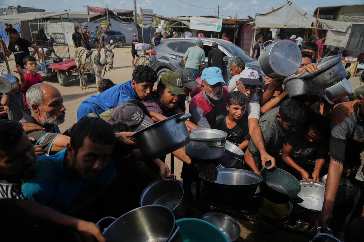 فلسطينيون ينتظرون الحصول على غذاء من إحدى التكيات في خان يونس