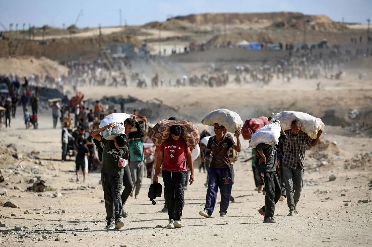 فلسطينيون يحملون أكياساً من المساعدات بالقرب من معبر نتساريم (أ.ف.ب)