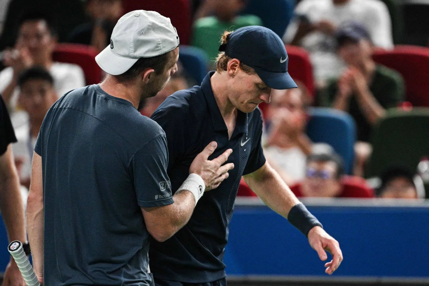 الإيطالي يانيك سينر يخرج من الملعب متكئاً على الهولندي تالون غريكسبوور (أ.ف.ب)