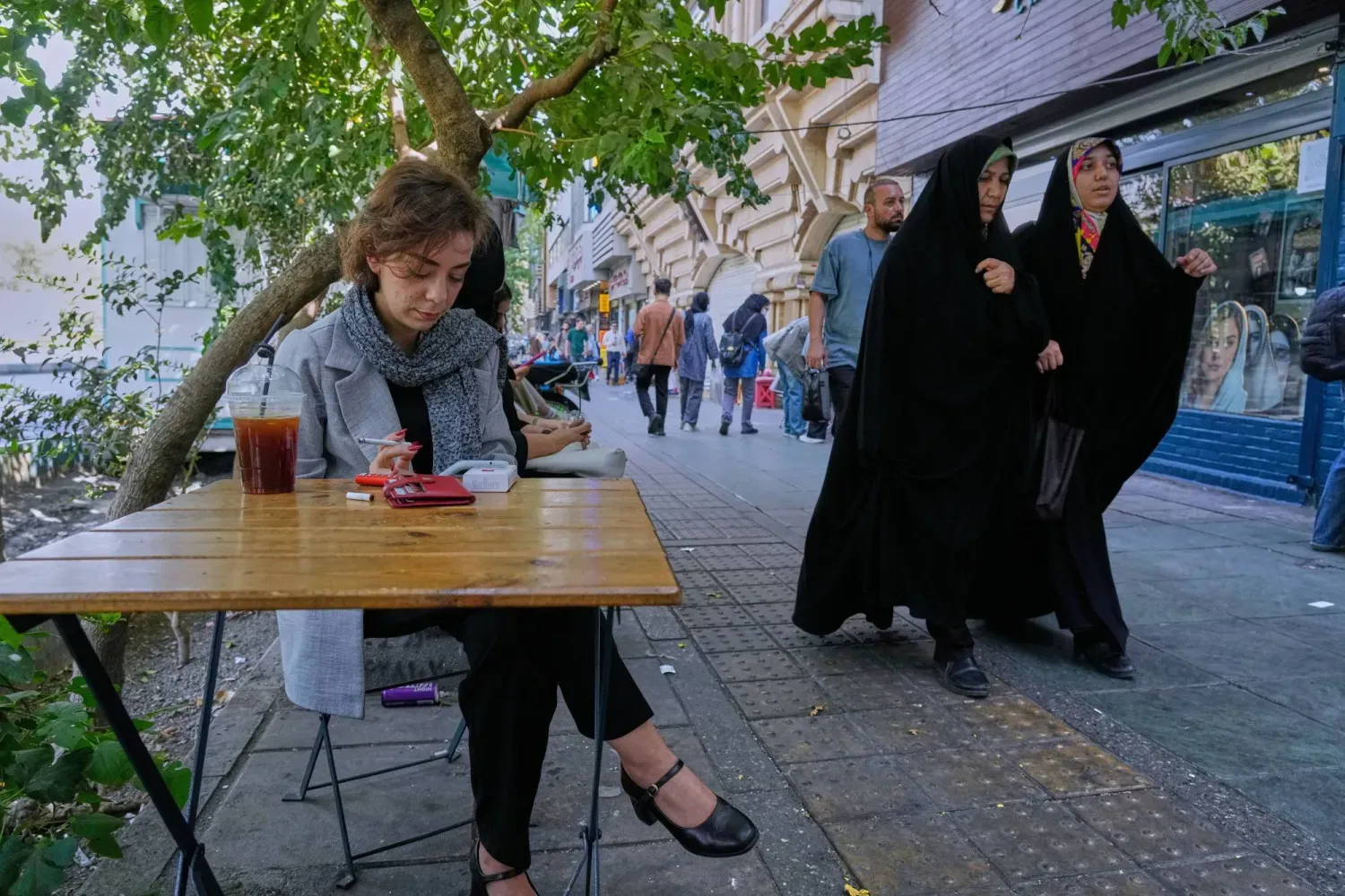Geçtiğimiz hafta Tahran'ın merkezindeki İnkılab (Devrim) Caddesi'nde bir kafenin önünde oturan bir kadın (AP)