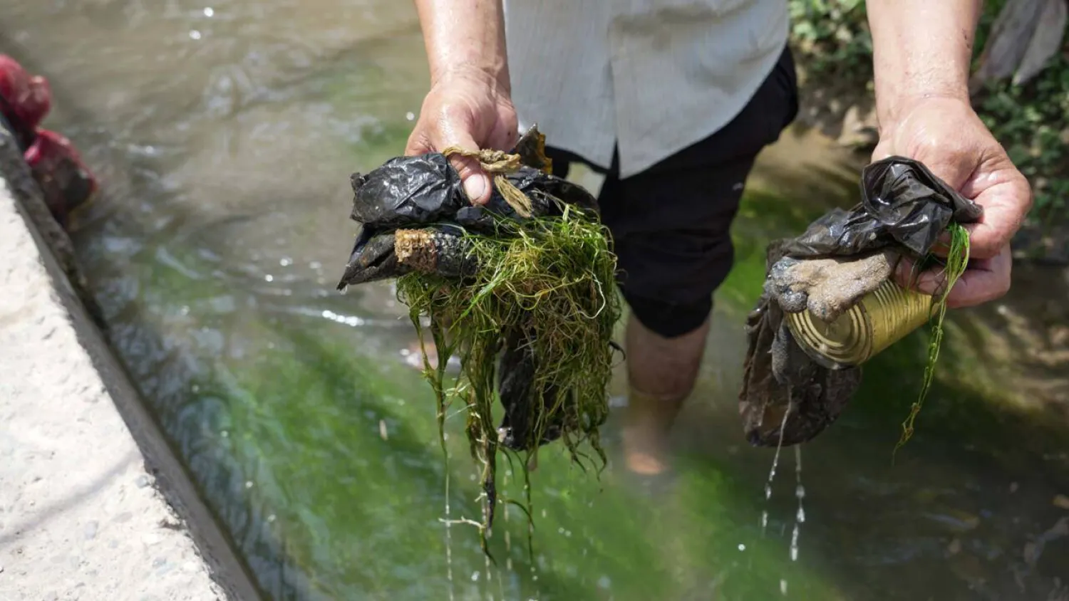 Tajik laborer Nematoullo Bassirov shows garbage he scooped from the stream running through his yard mountainous Central Asian country. STRINGER / AFP

