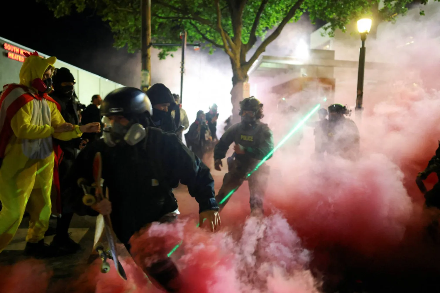 ضباط إنفاذ القانون يحاولون تفريق محتجين خارج مقر هيئة الهجرة والجمارك الأميركية في جنوب بورتلاند بولاية أوريغون الأحد (رويترز)