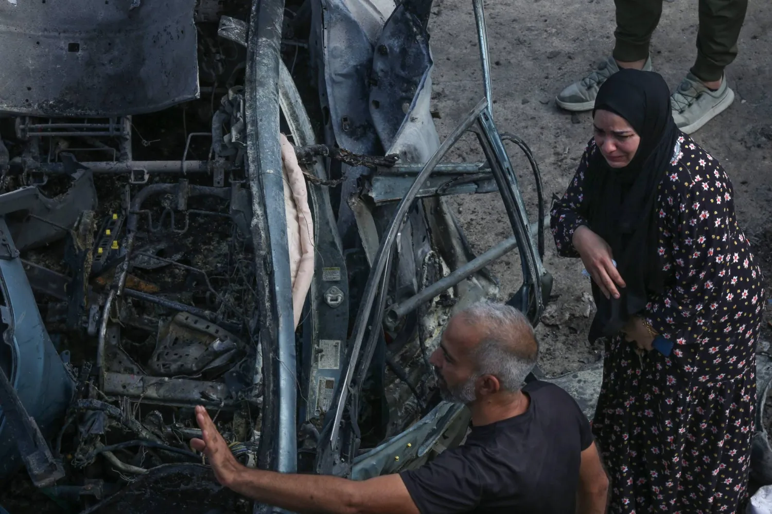 سيدة ورجل أمام السيارة التي استُهدفت بغارة إسرائيلية في منطقة زبدين في الجنوب وأدت إلى مقتل مصاب بتفجيرات «البيجر» وزوجته (أ.ف.ب)