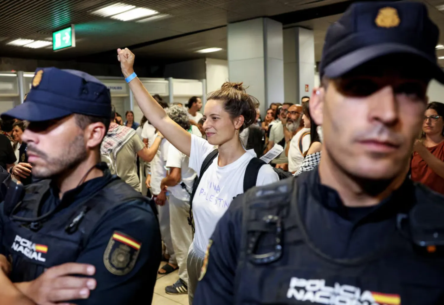 One of the Spanish activists who was part of the Global Sumud Flotilla and was detained by Israeli forces, gesture next to Police officers upon arrival at Adolfo Suarez Madrid-Barajas Airport in Madrid, Spain, October 5, 2025. REUTERS/Juan Medina 