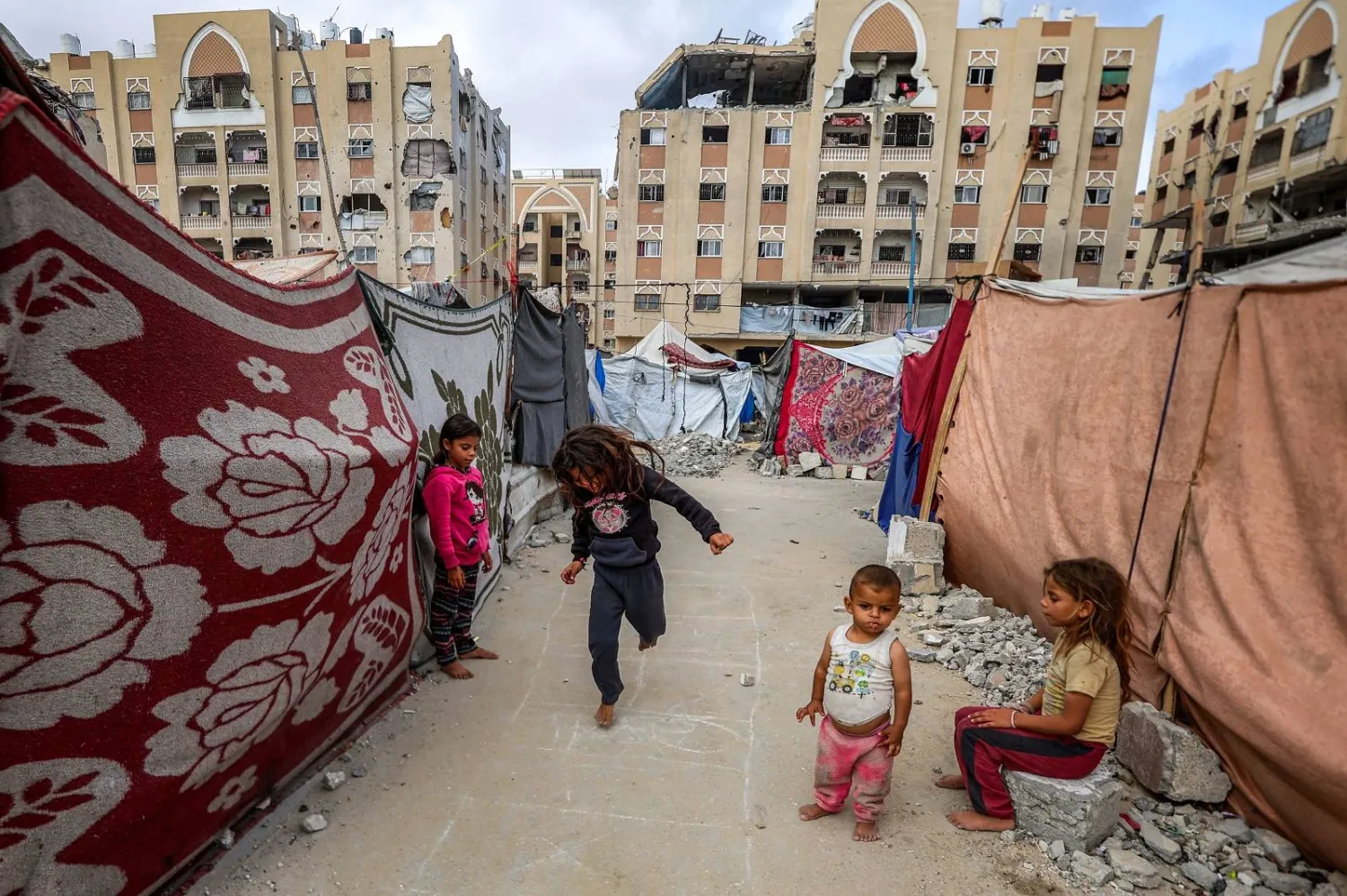 أطفال يلعبون خارج خيام تؤوي نازحين بخان يونس جنوب غزة (أ.ف.ب)