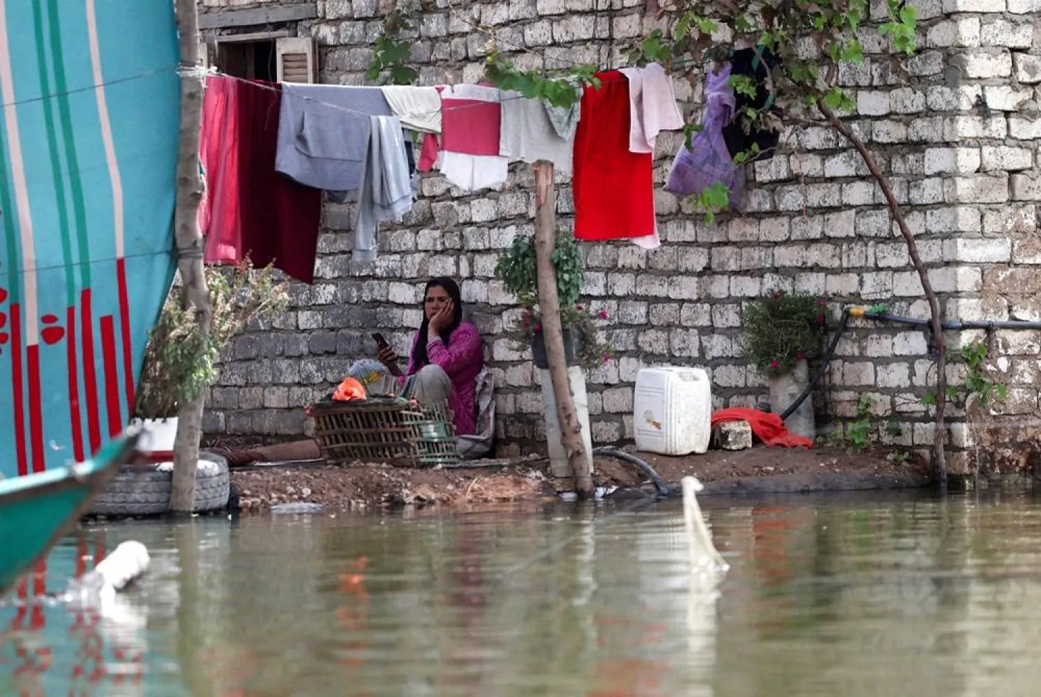 A woman sits near her flooded house in Dalhamo Village, near the Delta city of Ashmoun, in Menoufia Governorate, Egypt, October 5, 2025. (Reuters)