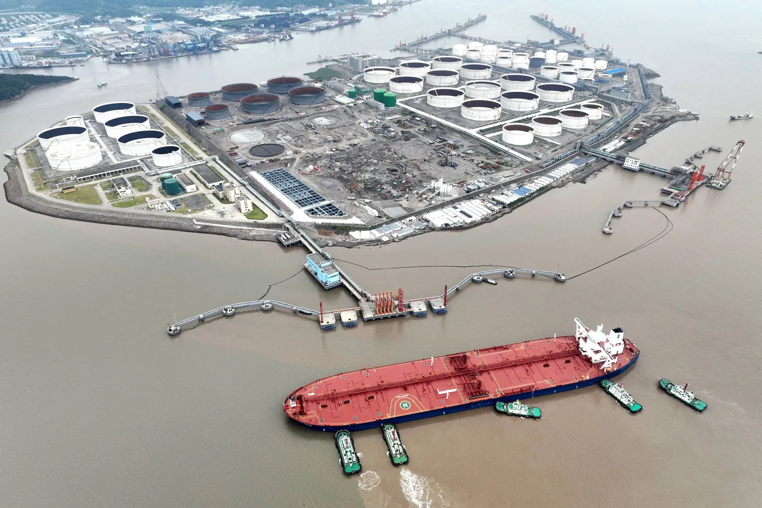 قاطرات تساعد ناقلة نفط خام على الرسو في محطة نفط قبالة جزيرة وايدياو في تشوشان بالصين (رويترز)