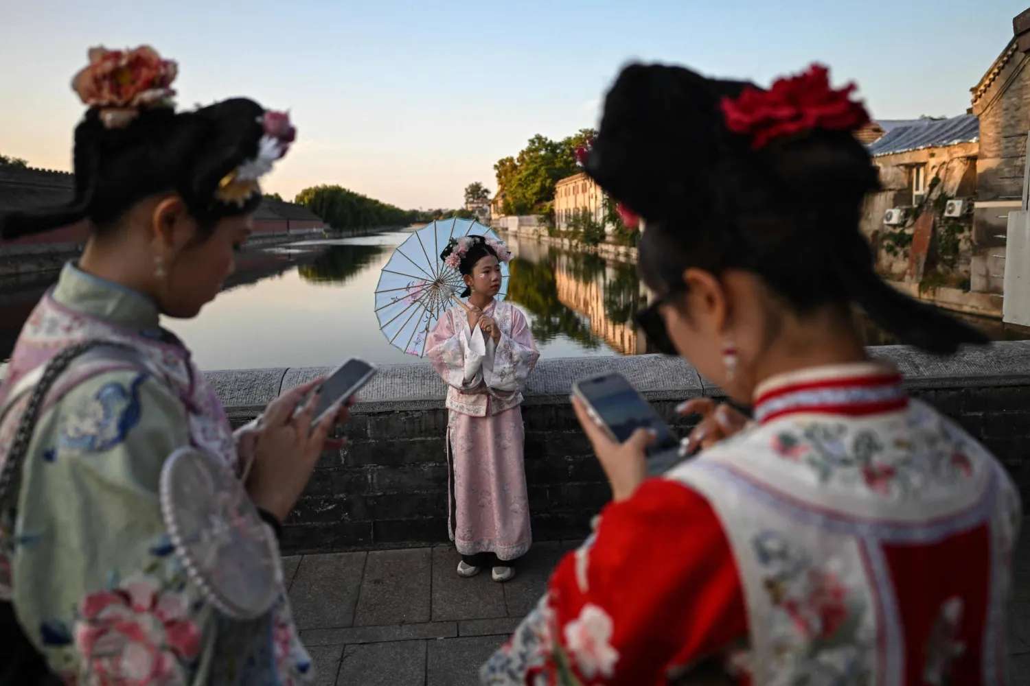Women wearing traditional Chinese costumes pose for photographs as they visit the surroundings of the Forbidden City in Beijing during China's National Day Golden Week holiday on October 6, 2025. (AFP)