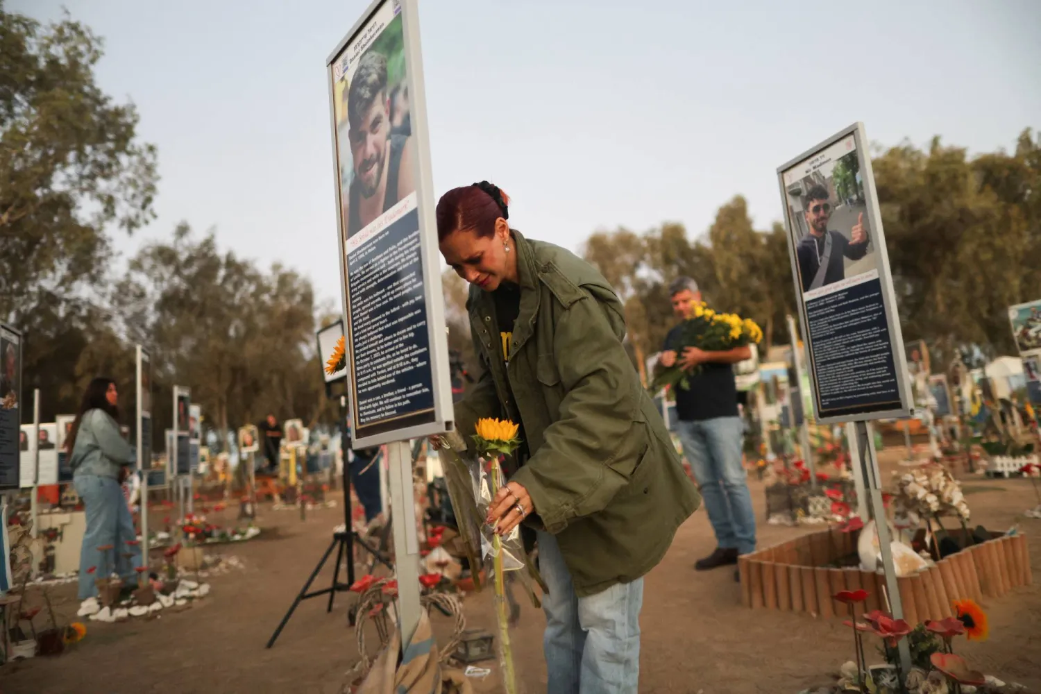 A woman places a flower as people grieve at the site of the Nova festival where partygoers were killed and kidnapped, on the two-year anniversary of the deadly October 7, 2023 attack on Israel by Hamas from Gaza, in Reim, southern Israel, October 7, 2025. (Reuters)