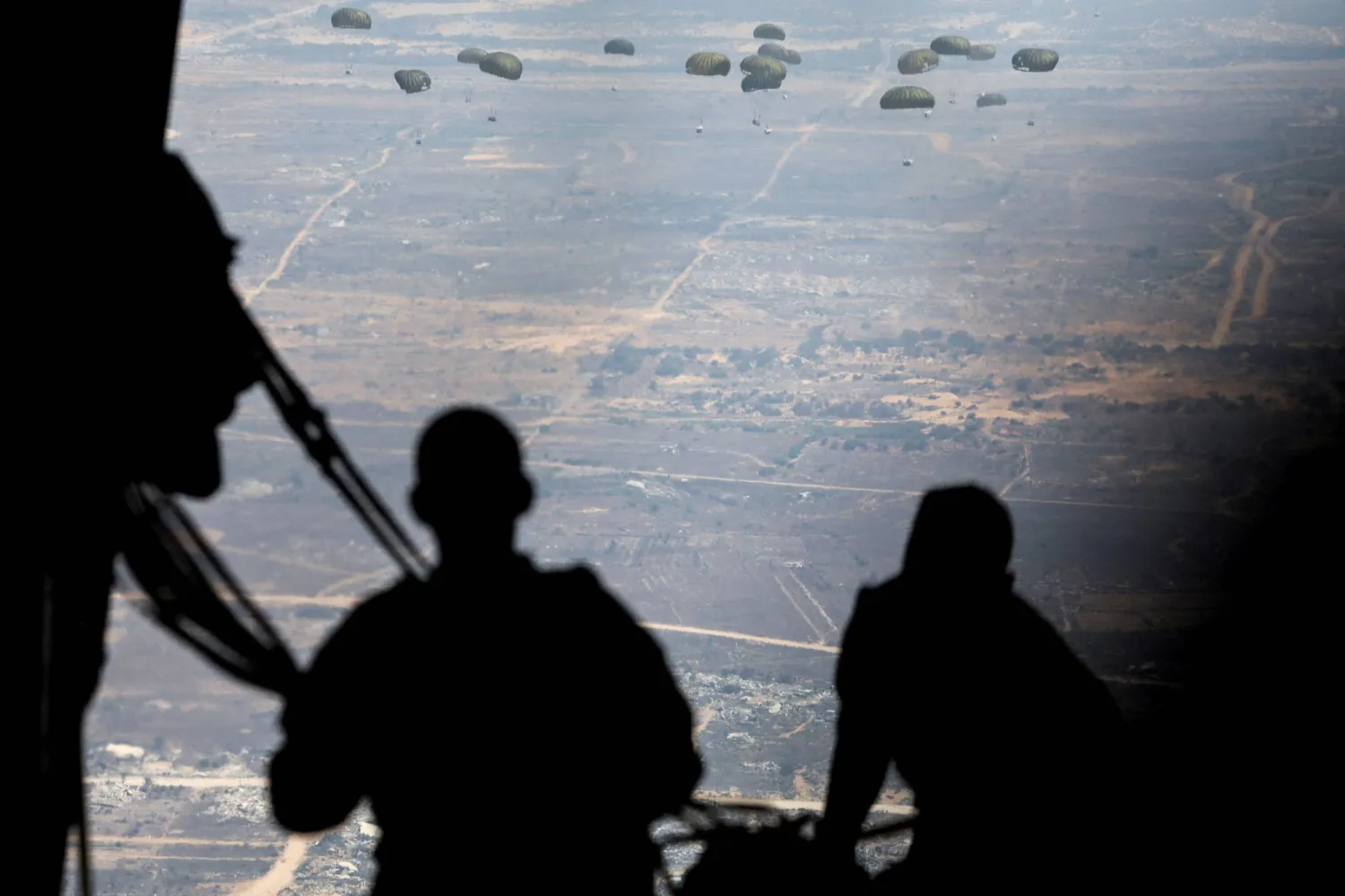 عناصر من سلاح الجو الأردني يسقطون رزم المساعدات من طائرة نقل فوق غزة (رويترز)