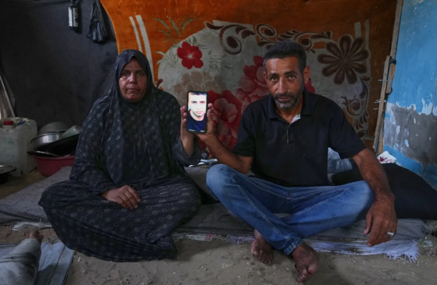 محمد النجار وزوجته يحملان جوالاً يظهر صورة ابنهما المفقود أحمد (أ.ب)