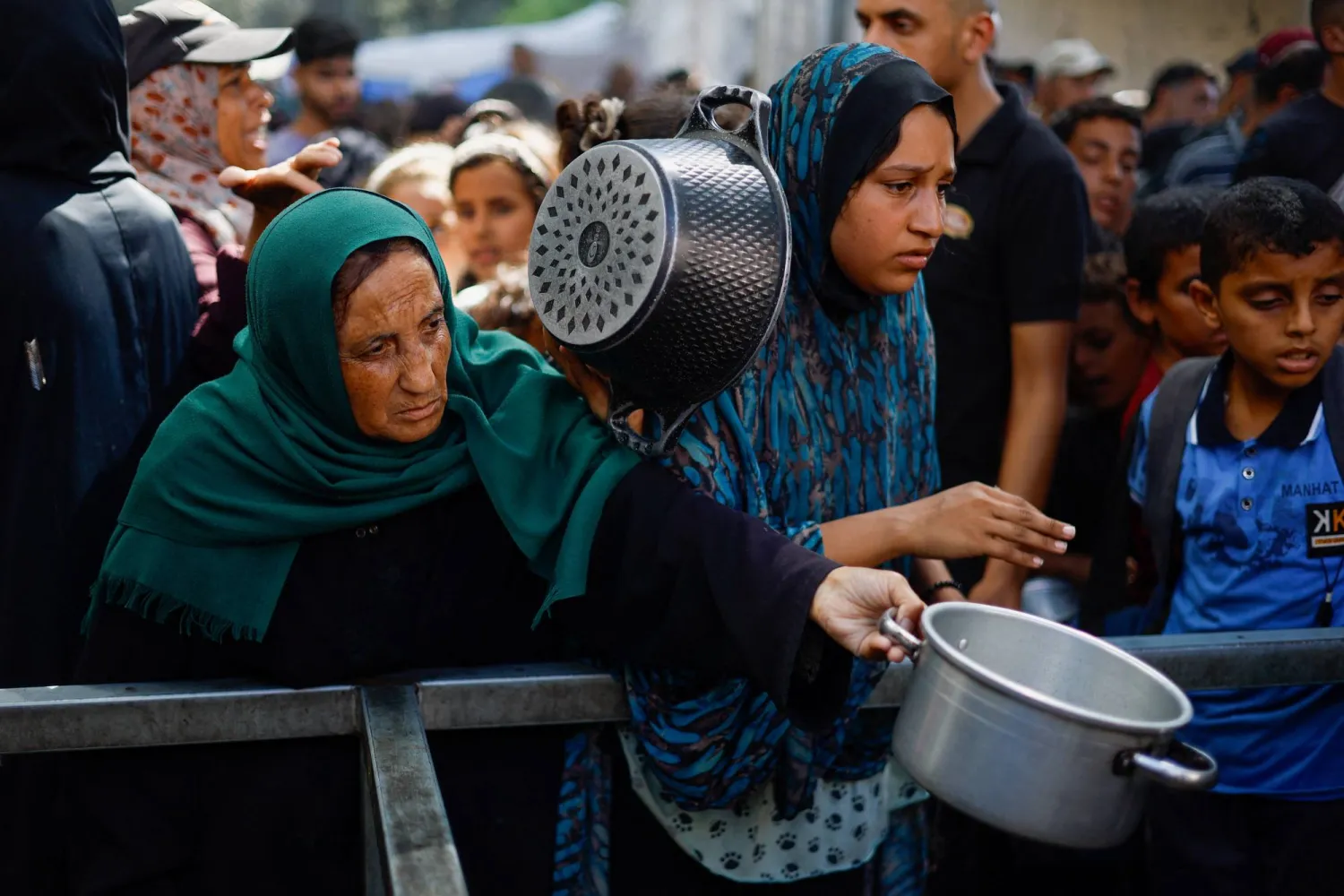 فلسطينيون يتجمعون لتلقي الطعام من مطبخ خيري في النصيرات وسط قطاع غزة 7 أكتوبر (رويترز)