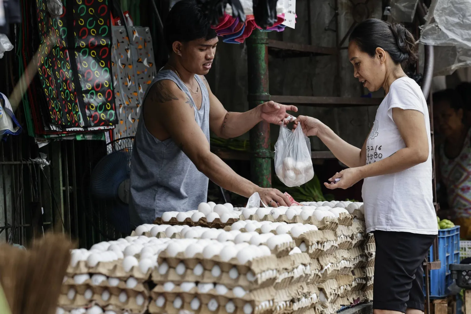 بائع (يسار) يسلم البيض الذي تم شراؤه إلى امرأة في الفلبين (إ.ب.أ)