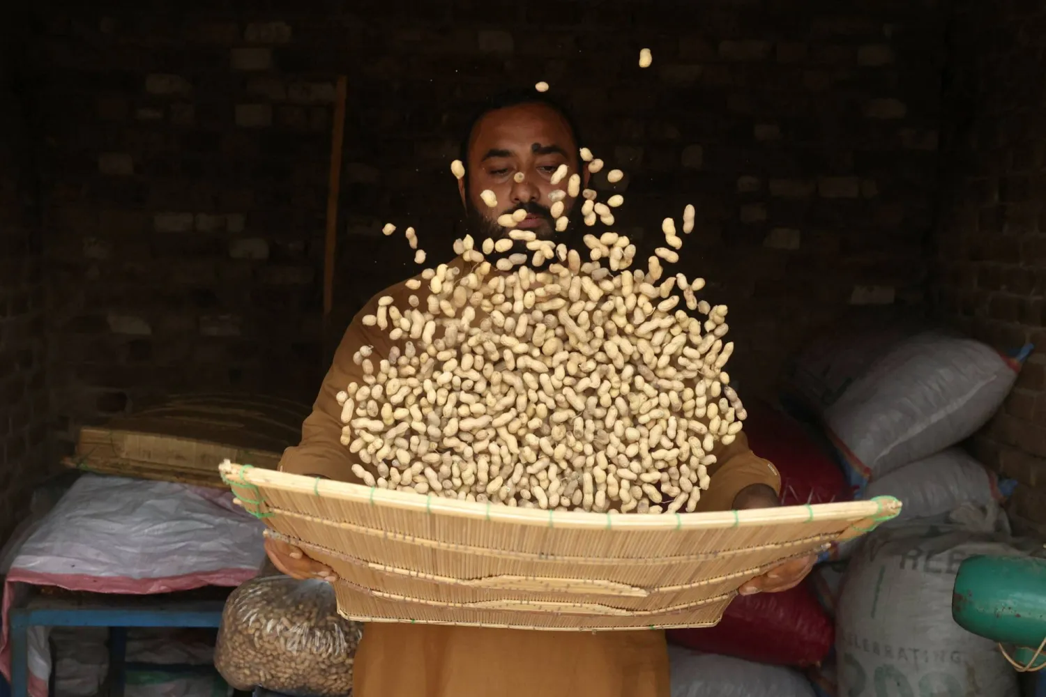 رجل ينخل الفول السوداني قبل بيعه في باكستان (رويترز)