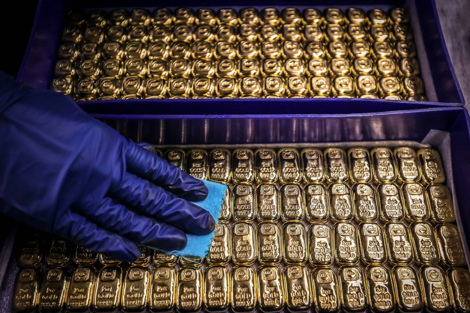 (FILES) A worker polishes gold bullion bars at the ABC Refinery in Sydney on August 5, 2020. (Photo by DAVID GRAY / AFP)
