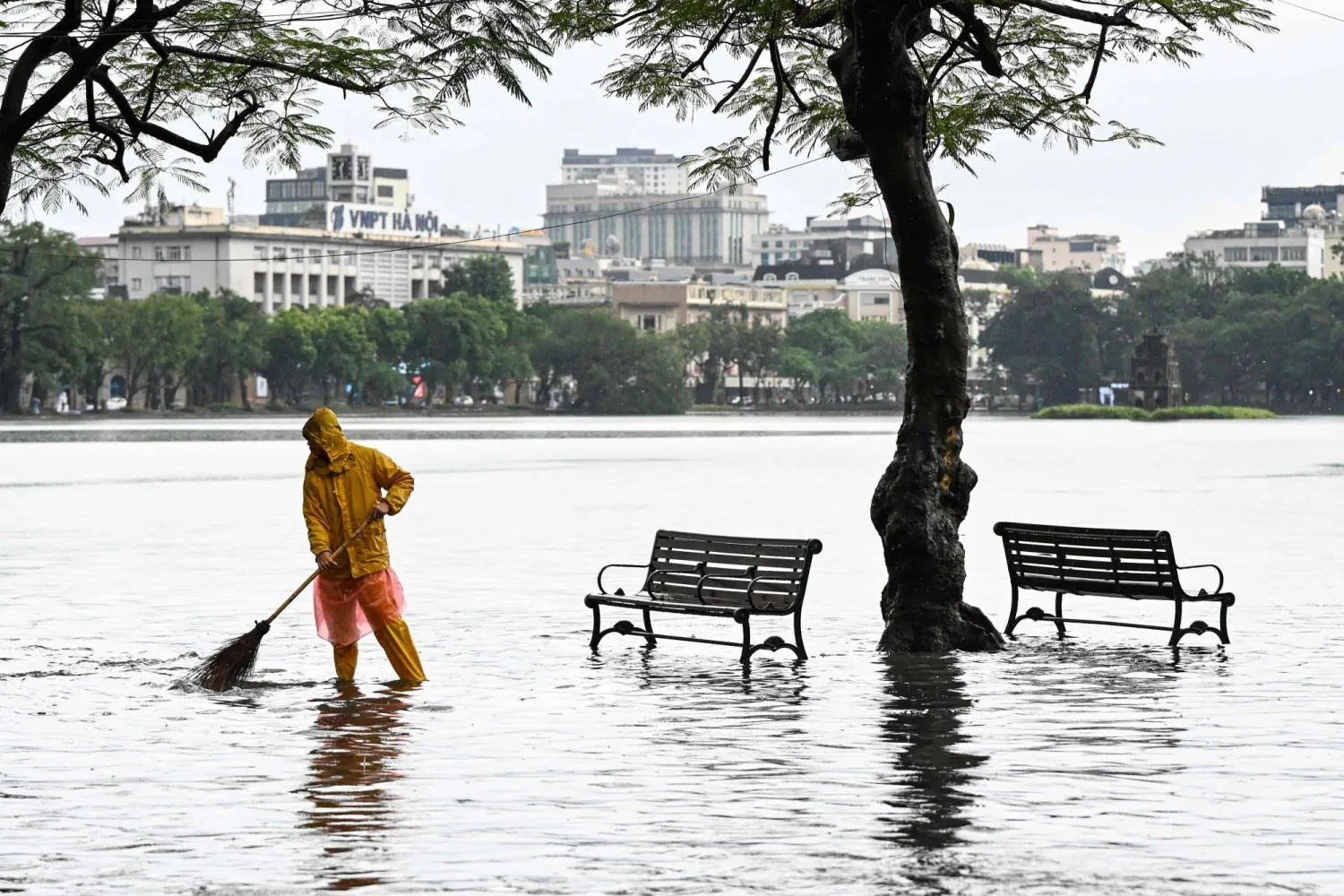A drainage worker sweeps the flooded edge of the Hoan Kiem Lake after heavy rain caused by Tropical Storm Matmo in Hanoi on October 7, 2025. (AFP)