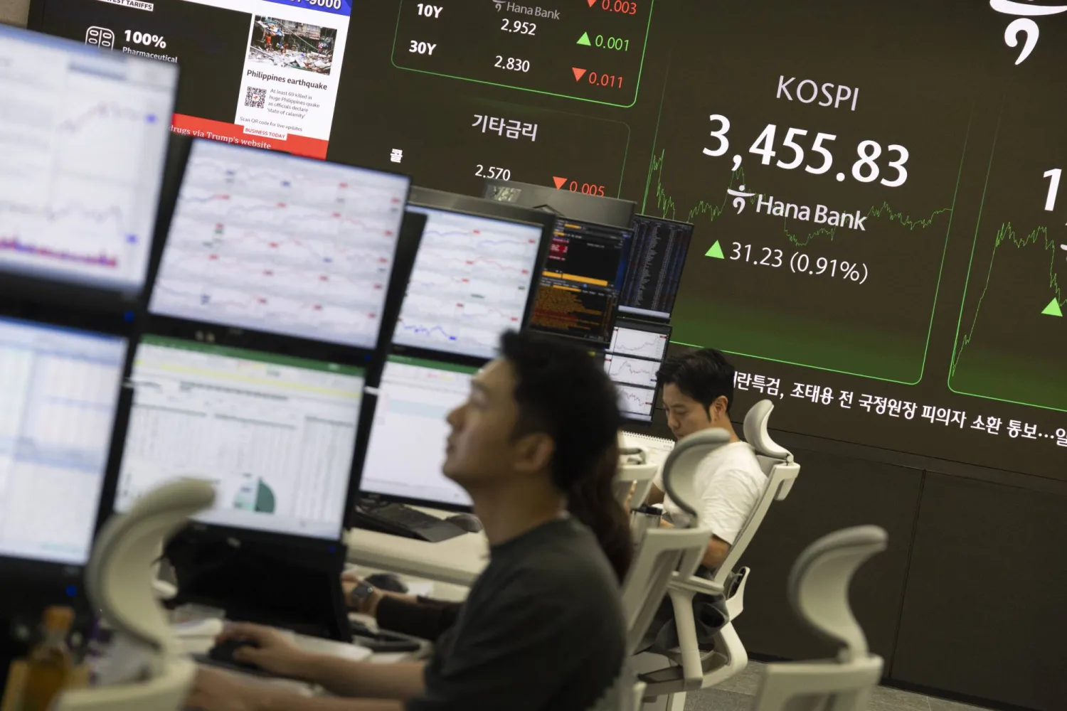 متداولون يعملون أمام الشاشات في «بنك هانا» بالعاصمة سيول (إ.ب.أ)