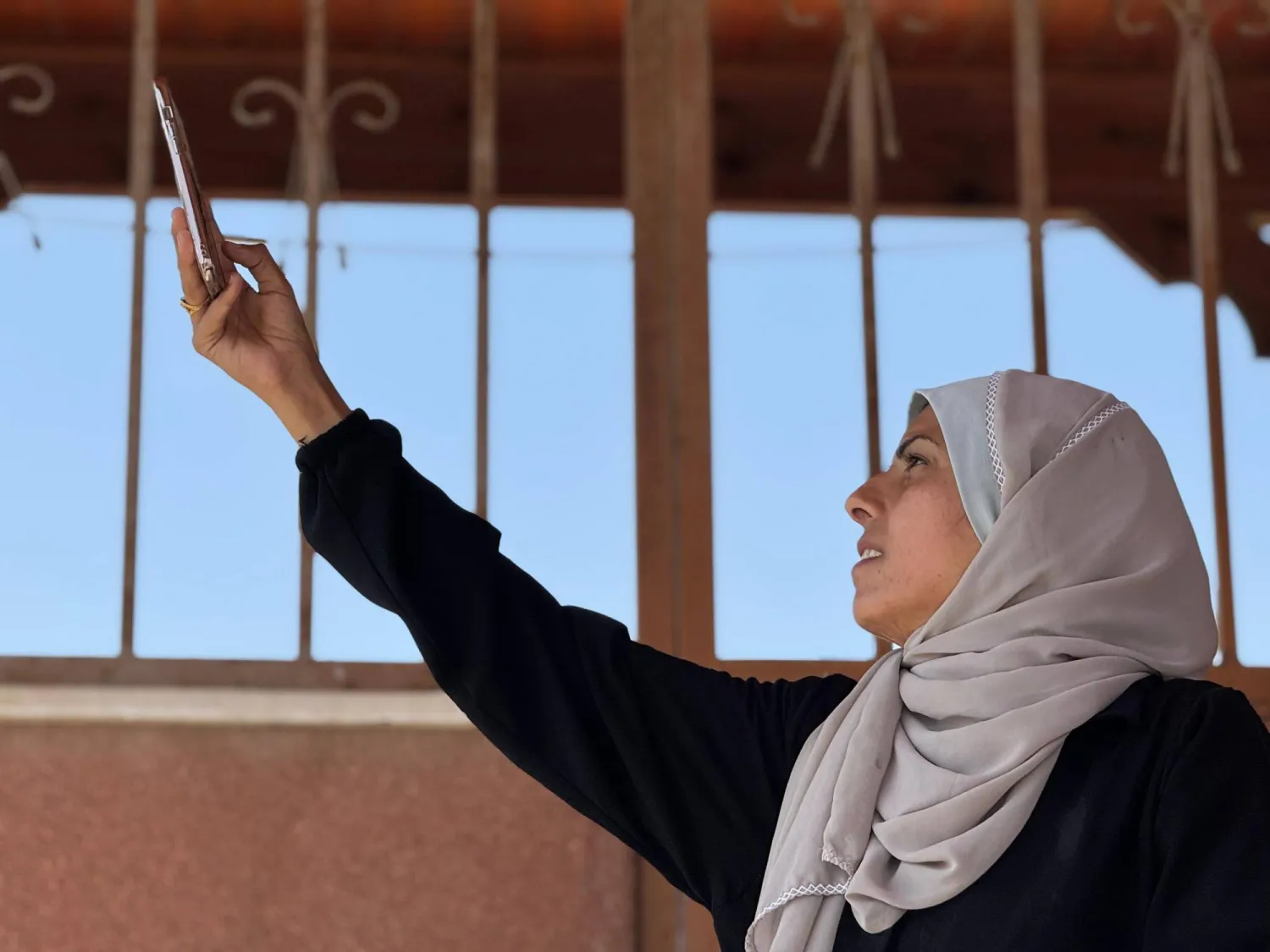 الصحافية الفلسطينية مريم أبو دقة تحاول ترفع هاتفها الجوال لالتقاط إشارة (إندبندنت عربية)