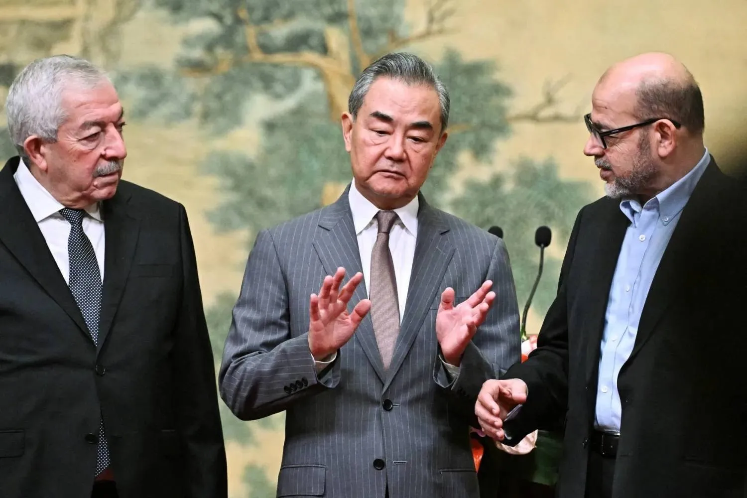 Chinese Foreign Minister Wang Yi mediates between Hamas official Mousa Abu Marzook (right) and Fatah official Mahmoud Aloul during a reconciliation round in July 2024 (Reuters) 