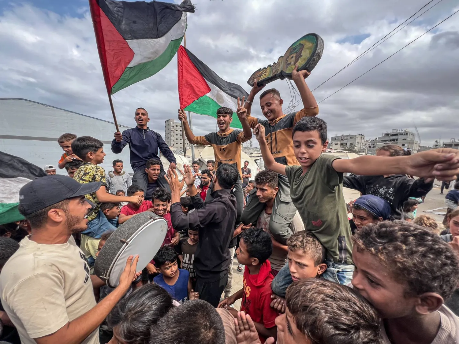 فلسطينيون يحتفلون في مخيم النصيرات بغزة أمس باتفاق وقف النار (د.ب.) وفي الإطار احتفالات أخرى في تل أبيب بنفس المناسبة (رويترز)
