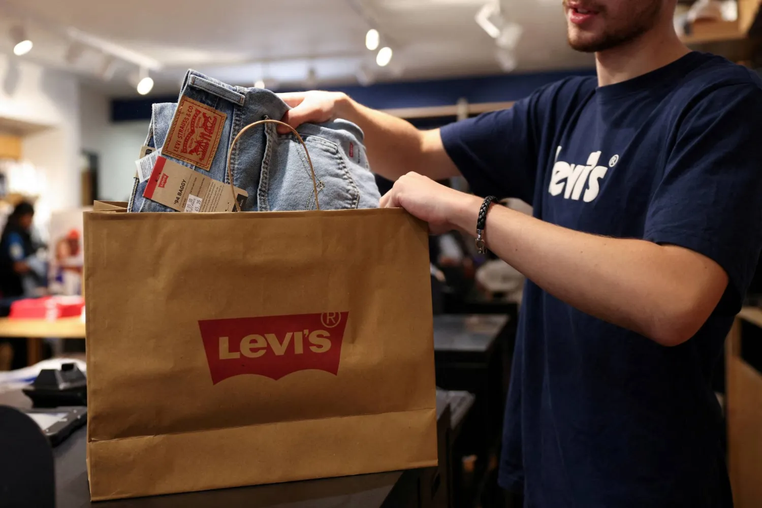 FILE PHOTO: A shop assistant bags a pair of jeans at the Levi’s outlet retail store at Bicester Village in Oxfordshire, Britain, August 21, 2024. REUTERS/Hollie Adams/File Photo