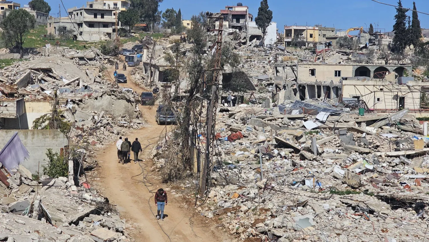 لبنانيون يعبرون وسط الركام في ميس الجبل المدمرة بجنوب لبنان (الشرق الأوسط)