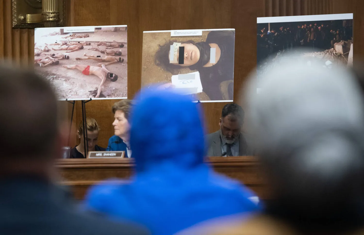 «قيصر» مخفياً هويته بمعطف أزرق خلال جلسة نقاش في الكونغرس الأميركي لقانون حماية المدنيين السوريين (أ.ف.ب)