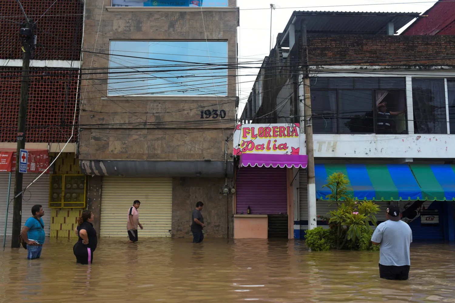 People wade through a flooded street after torrential rains that caused an overflow of rivers in Poza Rica, Veracruz state, Mexico, October 10, 2025. REUTERS/Rolando Ramos