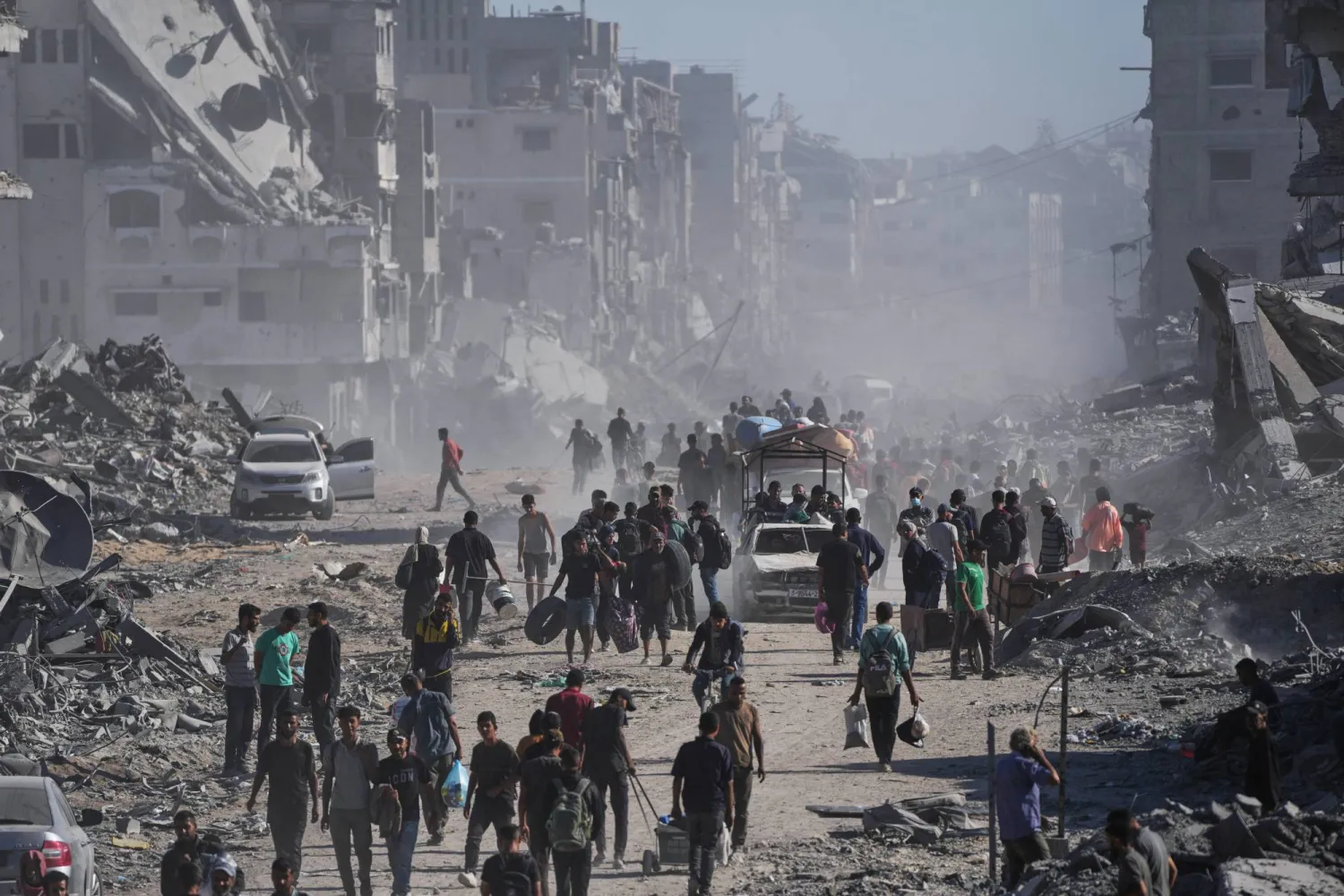 Displaced Palestinians carry their belongings as they walk along the heavily damaged Al-Jalaa Street in Gaza City, Saturday, Oct. 11, 2025, after Israel and Hamas agreed to a pause in their war and the release of the remaining hostages. (AP Photo/Abdel Kareem Hana)