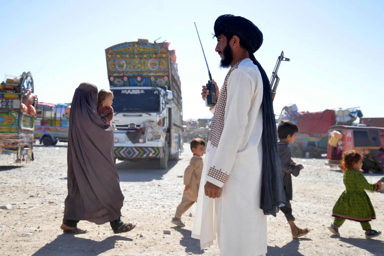  Pakistan'dan sınır dışı edilen Afganlar, Kandahar’daki kayıt merkezine giderken nöbet tutan bir Taliban güvenlik görevlisi (AFP)