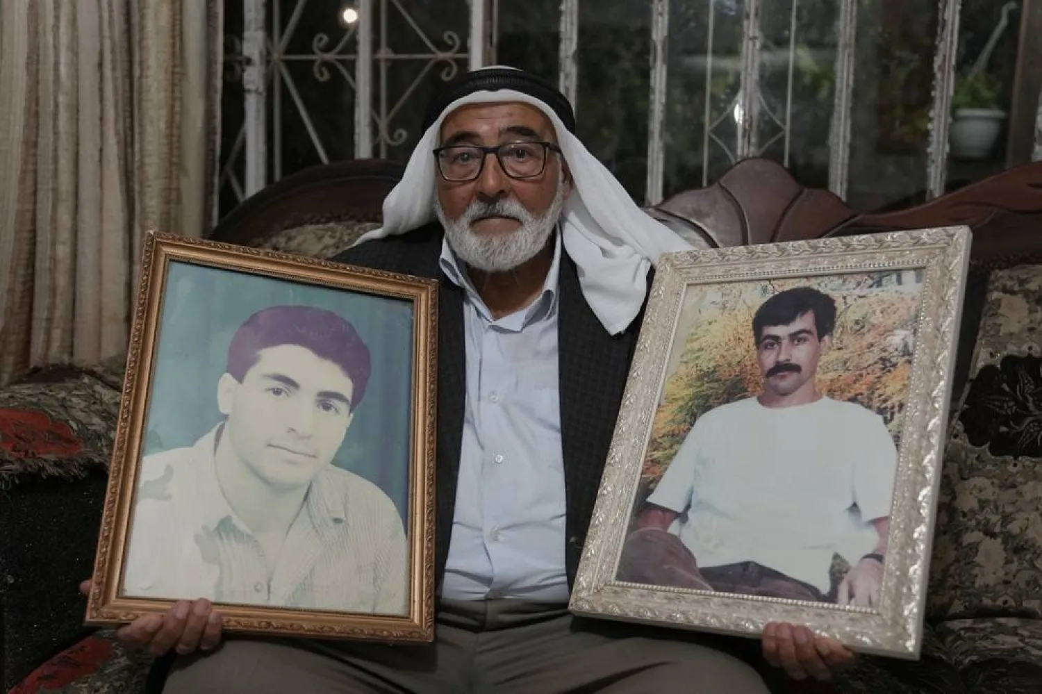 Yousef Shamasneh, 83, holds portraits of his two imprisoned sons, Abdel Jawad, right, and Mohammad, at his home in the West Bank village of Qatanna, west of Jerusalem, Friday, Oct. 10, 2025. (AP) 