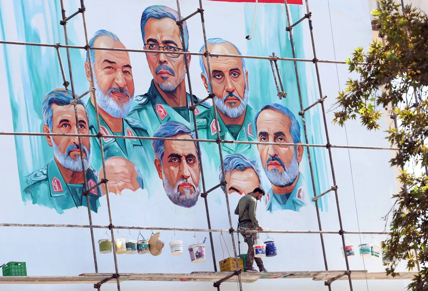 An artist paints a mural on a building in Tehran depicting senior military commanders killed in an Israeli strike. (EPA) 